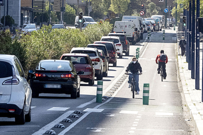 Usuarios del carril bici en la Avenida Isabel la Católica junto a una hilera de vehículos impulsados por motores de explosión a base de hidrocarburos. PHOTOGENIC