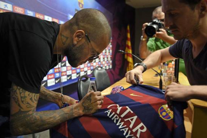 Dani Alves firma una camiseta antes de su comparecencia.-Foto:  AFP / LLUÍS GENÉ