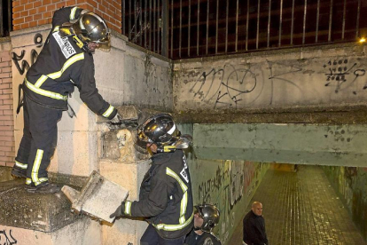 Los bomberos recogen las losas que se desprendieron de la pared del paso subterráneo.-Miguel Ángel Santos