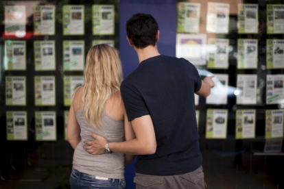 Una pareja observa carteles de alquiler y venta de viviendas.-E.M.