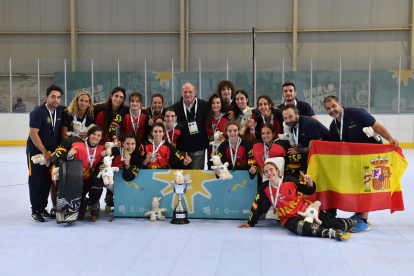 La selección española de hockey línea femenina con las vallisoletanas y con Ruiz y Andrés Portero a la derecha con la bandera nacional. / RFEP