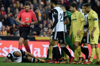El árbitro del Valencia-Villarreal se dirige a mostrar la segunda amarilla a Zaza, en el suelo.-AFP / JOSÉ JORDÁN