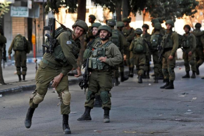 Un soldado israelí lanza un petardo contra un grupo de palestinos en Hebron durante un enfrentamiento, el pasado 13 de octubre.-EFE / ABED AL HASHLAMOUN