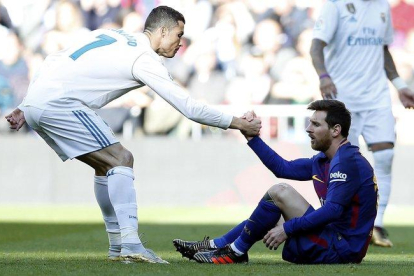 Cristiano ayuda a Messi a levantarse tras una falta que le cometieron en un clásico jugado en Madrid el 2017.-AP