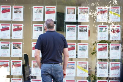 Un varón mira ofertas de viviendas en el escaparate de una inmobiliaria de Valladolid. ICAL