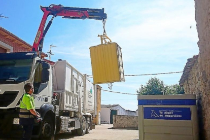 Un camión de la basura recoge los residuos del contenedor amarillo.