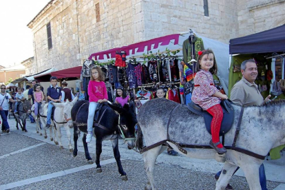 Los niños pasean en burro por delante de los puestos del mercado de oficios.-D. V.