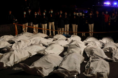 Voluntarios rezan ante los cadáveres de los fallecidos en el accidente de autobús en Taiwán.-REUTERS