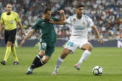 Asensio conduce el balón perseguido por Guardado durante el último Real Madrid-Betis.-JUANJO MARTÍN / EFE