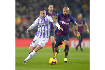 Guardiola corre tras el balón ante el marcaje de Vidal.-PHOTO-DEPORTE