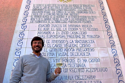 Juan de Benito, junto al soneto de su padre dedicado al vino verdejo, que luce en la pared del patio central de su bodega navarresa.-ARGICOMUNICACIÓN