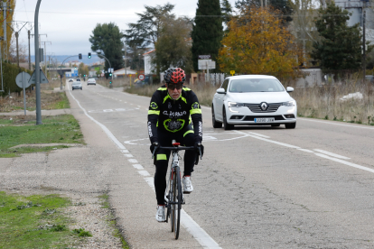 Un coche adelanta a un ciclista en el tramo del Camino Viejo de Simancas en el que se construirá una acera peatonal y un carril bici. J.M. LOSTAU