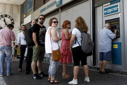 Atenienses hacen cola ayer para retirar dinero de un cajero automático en una sucursal del Banco Nacional de Grecia, en Atenas (Grecia).-Foto: EFE