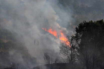 Miembros de las brigadas de extinción trabajan por apagar el incendio en la localidad de San Pedro Mallo, perteneciente al municipio de Toreno (León)