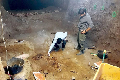 Dos operarios extraen restos óseos encontrados en la fosa común ubicada en la bodega de Los Alfredos.-ARMH
