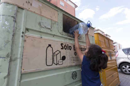 Una niña reciclando un envase de plástico en un contenedor en Valladolid.-Miguel Ángel Santos