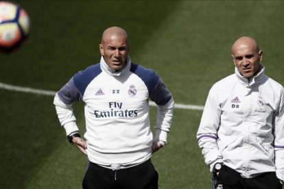 Zinedine Zidane, junto a su ayudante David Bettoni, en el entrenamiento de este sábado en Valdebebas.-EFE / MARISCAL