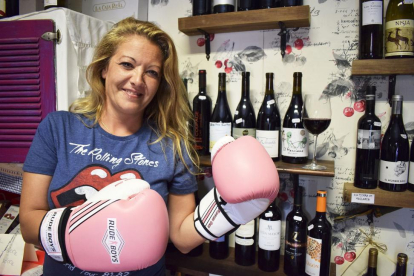 Eva Lucía Meneses, enfundada en sus guantes de kick boxing, con una copa y varios vinos de Cebreros, en su tienda de productos La Viña Bonita, situada en el centro de la capital abulense.-ARGI