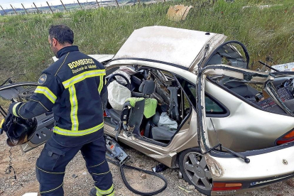 Un bombero examina el turismo siniestrado, con la carrocería cortada a radial para excarcelar el cuerpo de la fallecida.-EL MUNDO