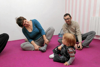 Imagen de un niño intentado imitar a sus padres mientras practican yoga-MONTSE ÁLVAREZ