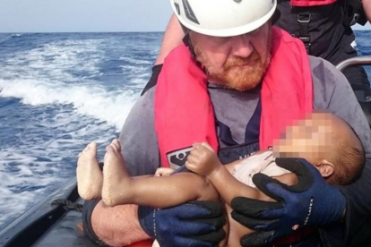 Un miembrod de la oenegé Sea Watch sostiene el cadáver de un bebé muerto recuperado de las aguas del Mediterráneo entre Libia e Italia.-CHRISTIAN BUETTNER