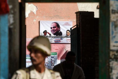 Un soldado custodia un centro de voto con un cartel electoral de Al Sisi.-AFP / KHALED DESOUKI