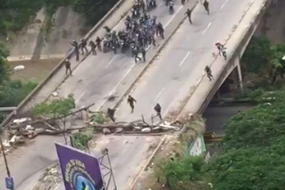La policía venezolana irrumpe, en motos, para dispersar una manifestación.-EL PERIÓDICO