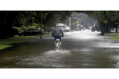 Un hombre circula con una bicicleta por una calle anegada en Beaumont (Tejas).-AP