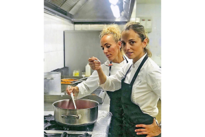 En la imagen, en primer plano, Yovana González y su hermana Vanesa comprobando un guiso en la cocina.-LA POSADA