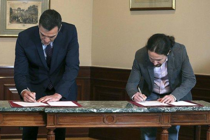 Pedro Sánchez y Pablo Iglesias firman el preacuerdo de coalición, el martes pasado en el Congreso.-DAVID CASTRO