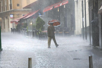Un hombre pasea con un paraguas durante el temporal de ayer-J.M. Lostau