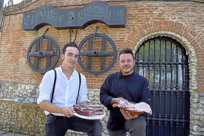 Rodrigo y Alfonso (con un cuarto de lechazo en cazuela de barro) a la entrada del mítico restaurante de Boecillo, que ambos regentan desde hace medio año.-ARGICOMUNICACIÓN
