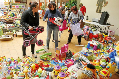 Varios asistentes recogen juguetes en el ‘hall’ del Centro Cívico de las Delicias.-J.M. Lostau