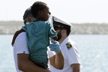 Un medico tiene en brazo un niño desembarcado del barco de la Guardia de Finanza en Pozzallo, Sicilia /-FRANCESCO RUTA (ANSA)