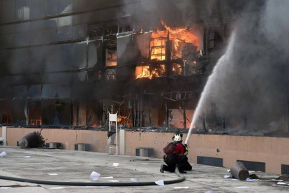 Un bombero intenta apagar el fuego de un edificio del complejo de la alcaldía de Chilpancingo.-Foto: AFP / YURI CORTEZ