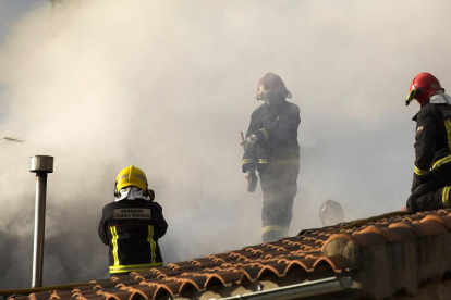 Un grupo de bomberos trabaja en el tejado de la vivienda.-ICAL