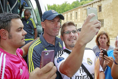 Dos aficionados del Real Madrid se hacen un ‘selfie’ con el técnico del Real Madrid B, Zinedine Zidane, justo a su llegada a Medina de Rioseco.-J. M. Lostau