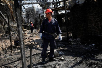 Un bombero inspecciona una de las viviendas quemadas por las llamas en la ciudad de Mati, próxima a Atenas.-ALKIS KONSTANTINIDIS (REUTERS)