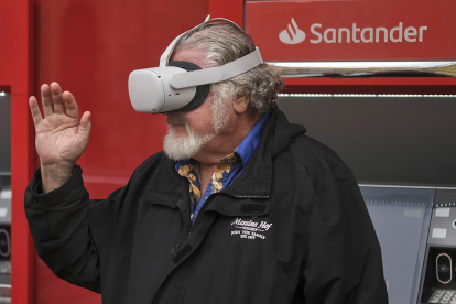 Una persona mayor utiliza unas gafas de realidad virtual en un cajero automático.-ENRIQUE CARRASCAL.