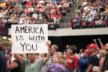 Un seguidor de Trump muestra un cartel con la frase "América te ama" en el mitin del presidente de Iowa.-SCOTT OLSON / AFP