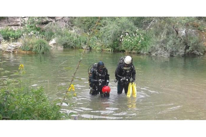 Dos efectivos del GEAS de la Guardia Civil inspeccionan el río con el objetivo de localizar el cuerpo del joven.-GC
