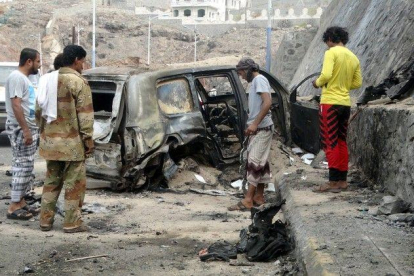 Varias personas contemplan los efectos del atentado con coche bomba en el que ha muerto el gobernador de Aden.-REUTERS