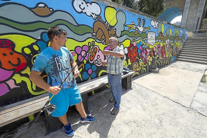Dos pescadores delante de uno de los murales de los alrededores de la Playa de Las Moreras.-PHOTOGENIC / PABLO REQUEJO