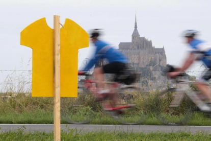 Uno ciclistas pasan cerca del Mont de Saint Michel, donde el sábado comienza el Tour.-AFP / KENZO TRIBOUILLARD