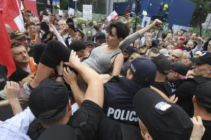Un grupo de personas intentan romper la barrera formada por la policia durante una protesta en Polonia-BARTLOMIEJ ZBOROWSKI
