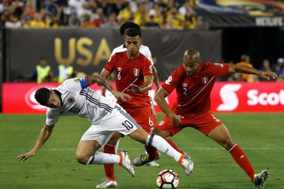 El colombiano James Rodriguez pugna por el balón con los peruanos Alberto Rodriguez y Miguel Trauco.-EFE