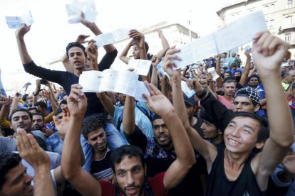REUTERS / LASZLO BALOGH 

Los refugiados muestran sus billetes de tren con indignación mientras esperan que los trenes vuelvan a circular en la estación de Keleti.