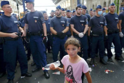 REUTERS / LASZLO BALOGH 

Una niña fotografiada frente a los policías que impiden la entrada de inmigrantes en la estación de trenes de Keleti, en Budapest, este martes.
