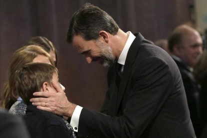 El rey Felipe consuela a un niño durante el funeral institucional celebrado en la basílica de la Sagrada Familia EFE ALBERTO ESTÉVEZ