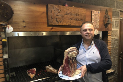 Fernando, en su restaurante, junto a una de sus afamadas piezas de carne rojas de buey, su especialidad-